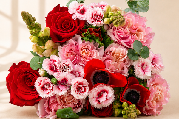 Red roses, pink carnations and green accents in a hand-tied holiday bouquet