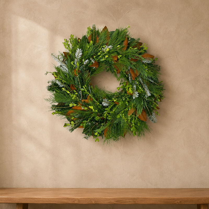 Classic Evergreen fresh wreath of boxwood, magnolia, Leyland cypress, pine, and Fraser fir on a plaster wall above a wood bench
