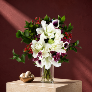 Cozy Christmas arrangement of white lilies, calla lilies and red berries in a glass vase