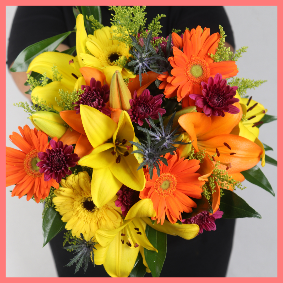 The Autumn Vibes bouquet includes mixed stems of lilies, gerbera daisies, CDN pompoms, eryngium, cocculus, aster, and pittosporum!
