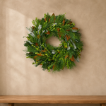 Classic Evergreen fresh wreath of boxwood, magnolia, Leyland cypress, pine, and Fraser fir on a plaster wall above a wood bench