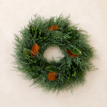 Merry & Bright fresh 22-inch wreath of Carolina Sapphire cypress, boxwood, and magnolia leaves on a plaster wall
