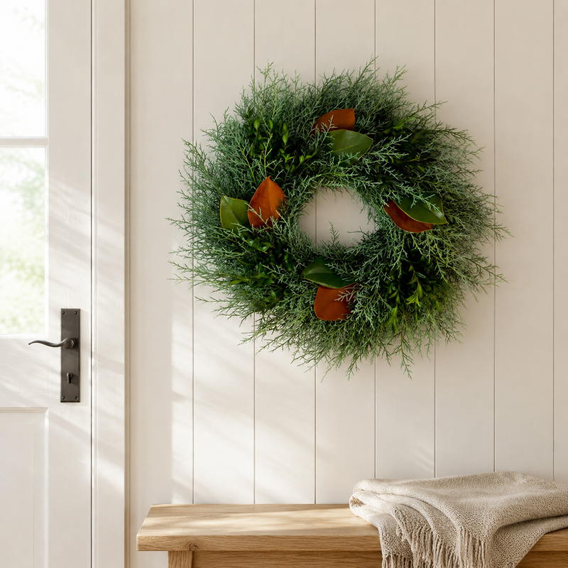 Merry & Bright wreath on a white shiplap wall above a wood bench, with Carolina Sapphire cypress, boxwood, and magnolia leaves