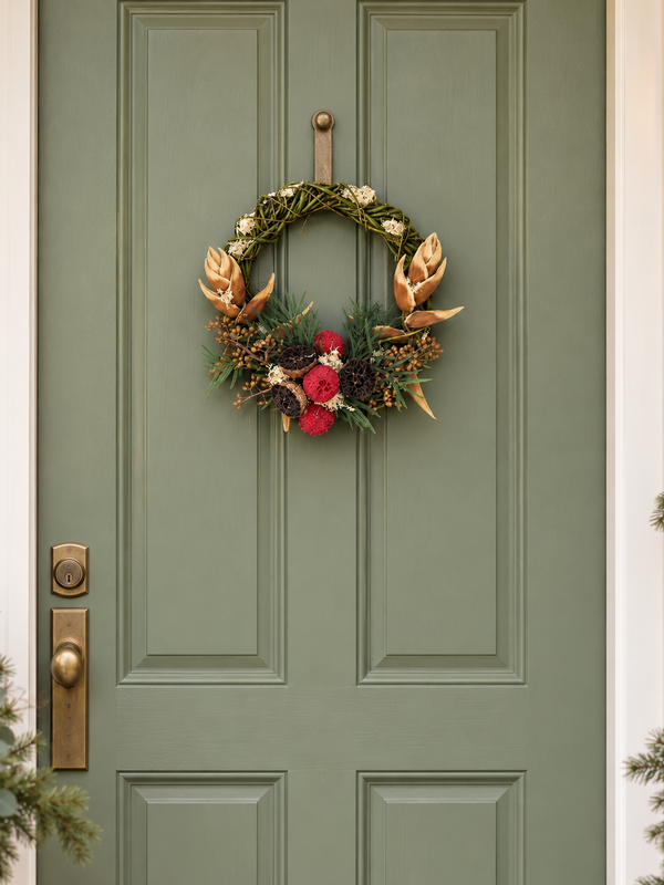 The Bronze Willow Wreath hanging on a sage green front door