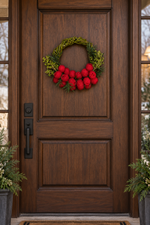 The Cranberry Willow Wreath hanging on a dark wood front door