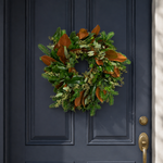 The Evergreen Edit wreath hanging on a navy front door
