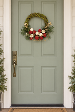 The Jingle Willow Wreath hanging on a sage green front door