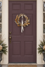 The Starlight Wreath hanging on a deep plum front door with a cream ribbon