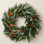 The Welcome Wreath fresh wreath of Fraser fir, blue-green baby eucalyptus, magnolia, and pinecones on a plaster wall